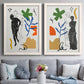 Set of two white barnwood framed canvas prints depicting paired graphic figurative collages with black linework, bold green blue orange shapes, and classical statue poses above a sofa in a contemporary living room.