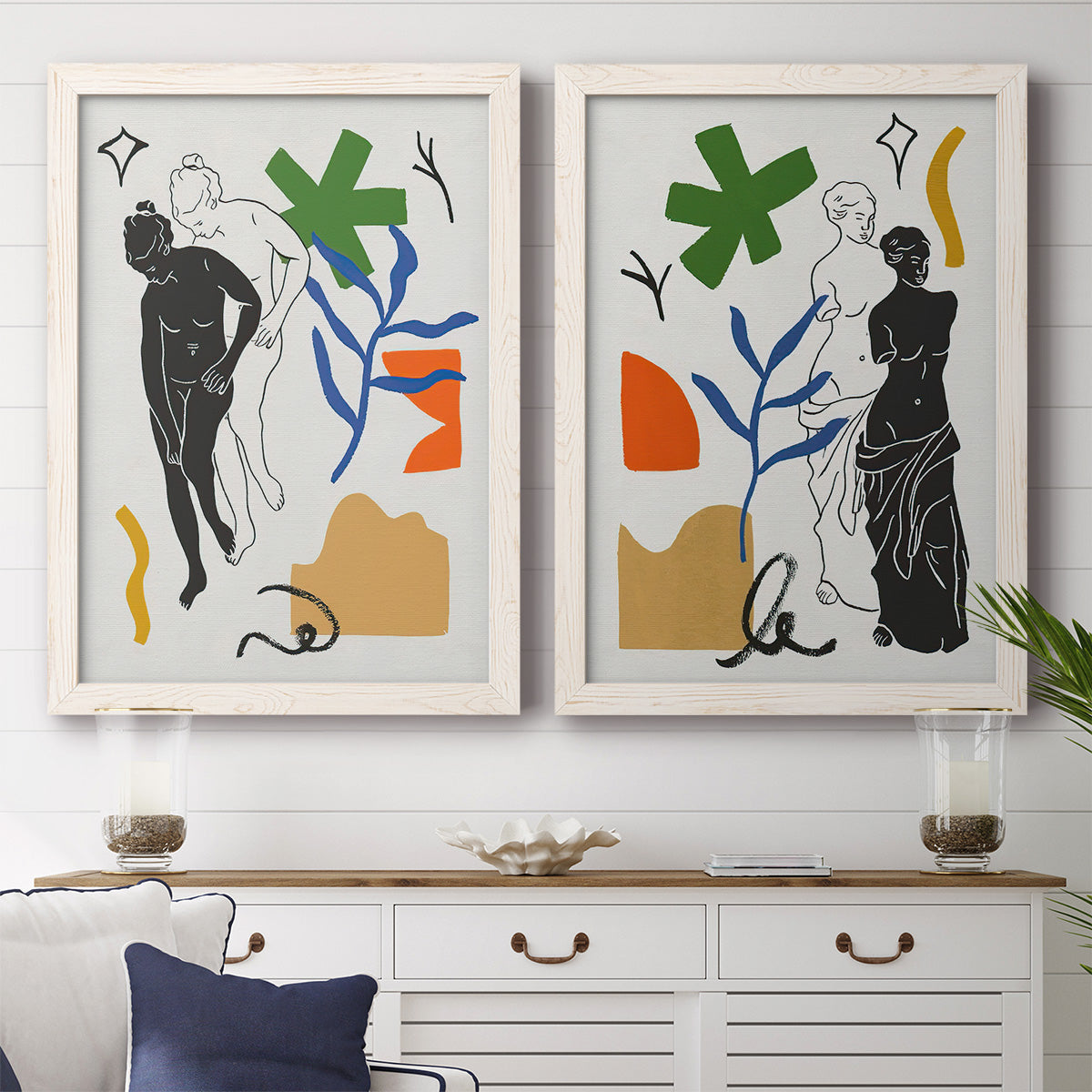 Set of two white barnwood framed canvas prints depicting a coordinated art pair of stylized female figures surrounded by botanical and geometric symbols rendered as graphic figurative collages above a dining room sideboard.