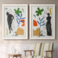 Set of two white barnwood framed canvas prints depicting two graphic figurative collages featuring stylized female figures surrounded by botanical and geometric symbols above a sideboard in a cozy sitting room.