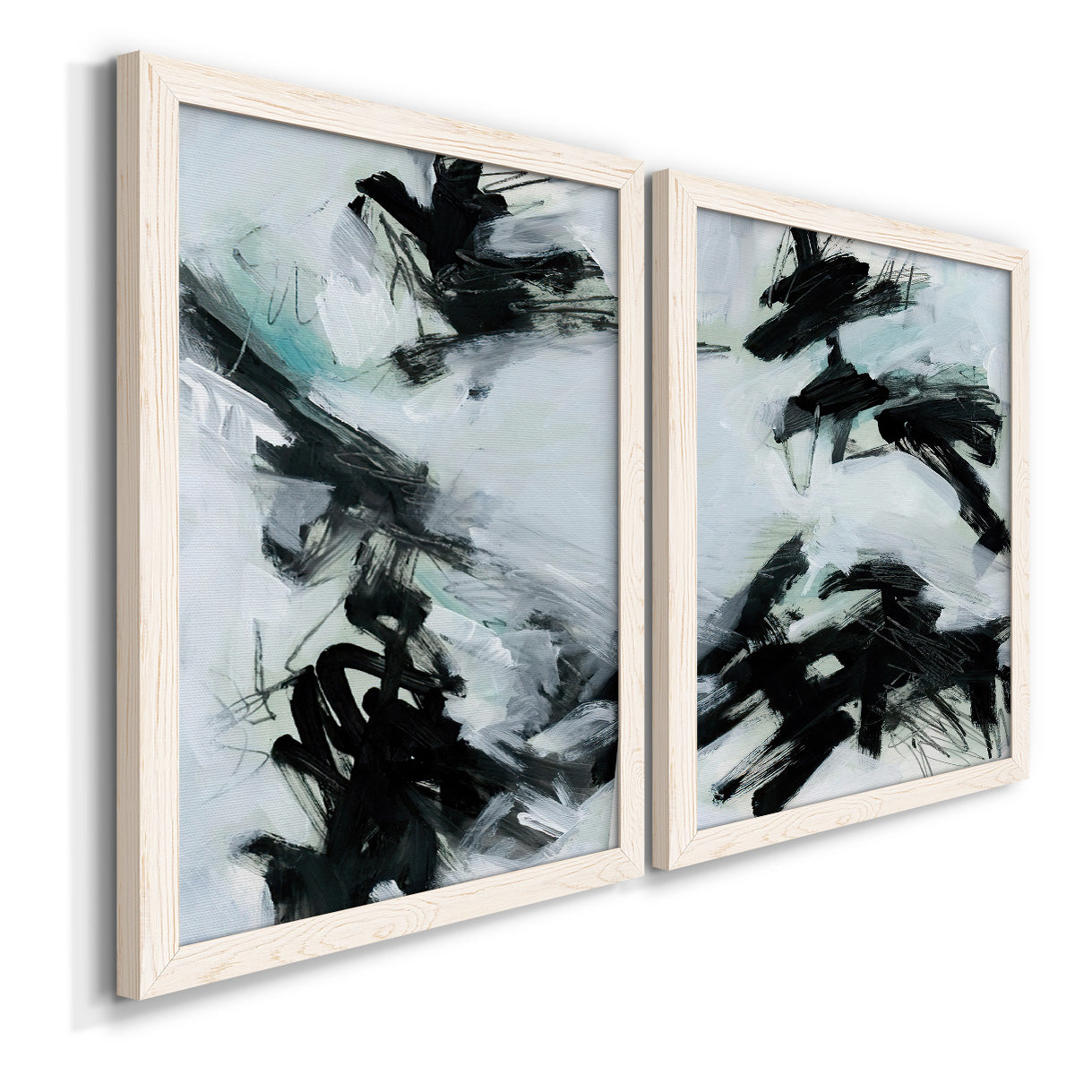 Angled view of a set of two white barnwood framed canvas prints featuring two gestural ocean-inspired abstracts featuring sweeping black brushstrokes over pale blue-gray fields.