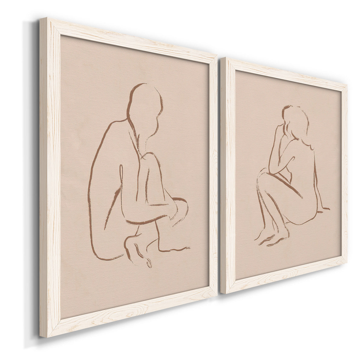 Angled view of a set of two white barnwood framed canvas prints featuring two minimalist figurative sketches featuring seated female figures drawn with single flowing lines.