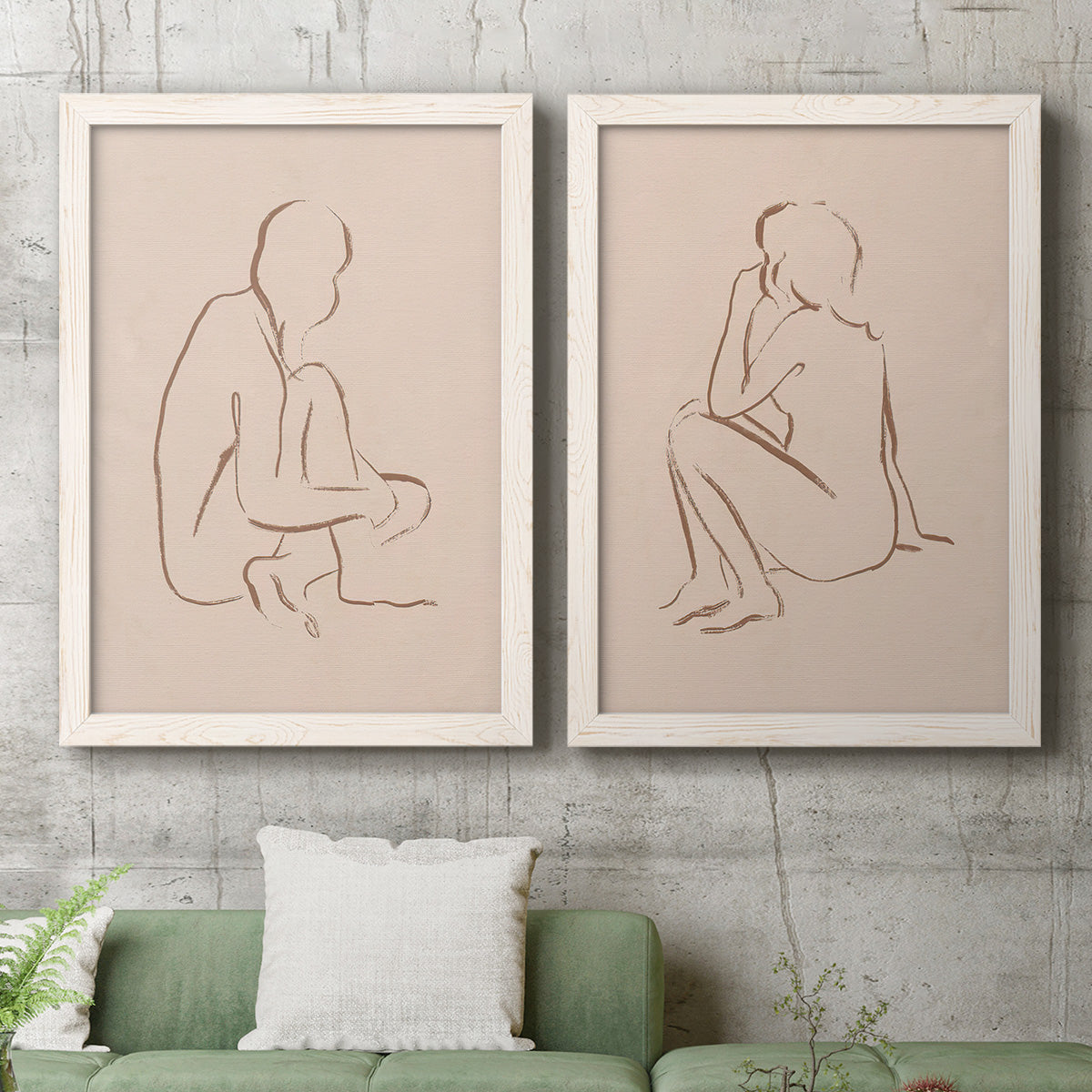 Set of two white barnwood framed canvas prints depicting a coordinated art pair of seated female figures drawn with single flowing lines rendered as minimalist figurative sketches above a sofa in a modern living room.