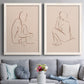 Set of two white barnwood framed canvas prints depicting paired minimalist figurative sketches with warm brown contours, relaxed poses, and blush cream grounds above a sofa in a contemporary living room.
