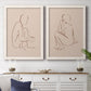 Set of two white barnwood framed canvas prints depicting a coordinated art pair of seated female figures drawn with single flowing lines rendered as minimalist figurative sketches above a dining room sideboard.