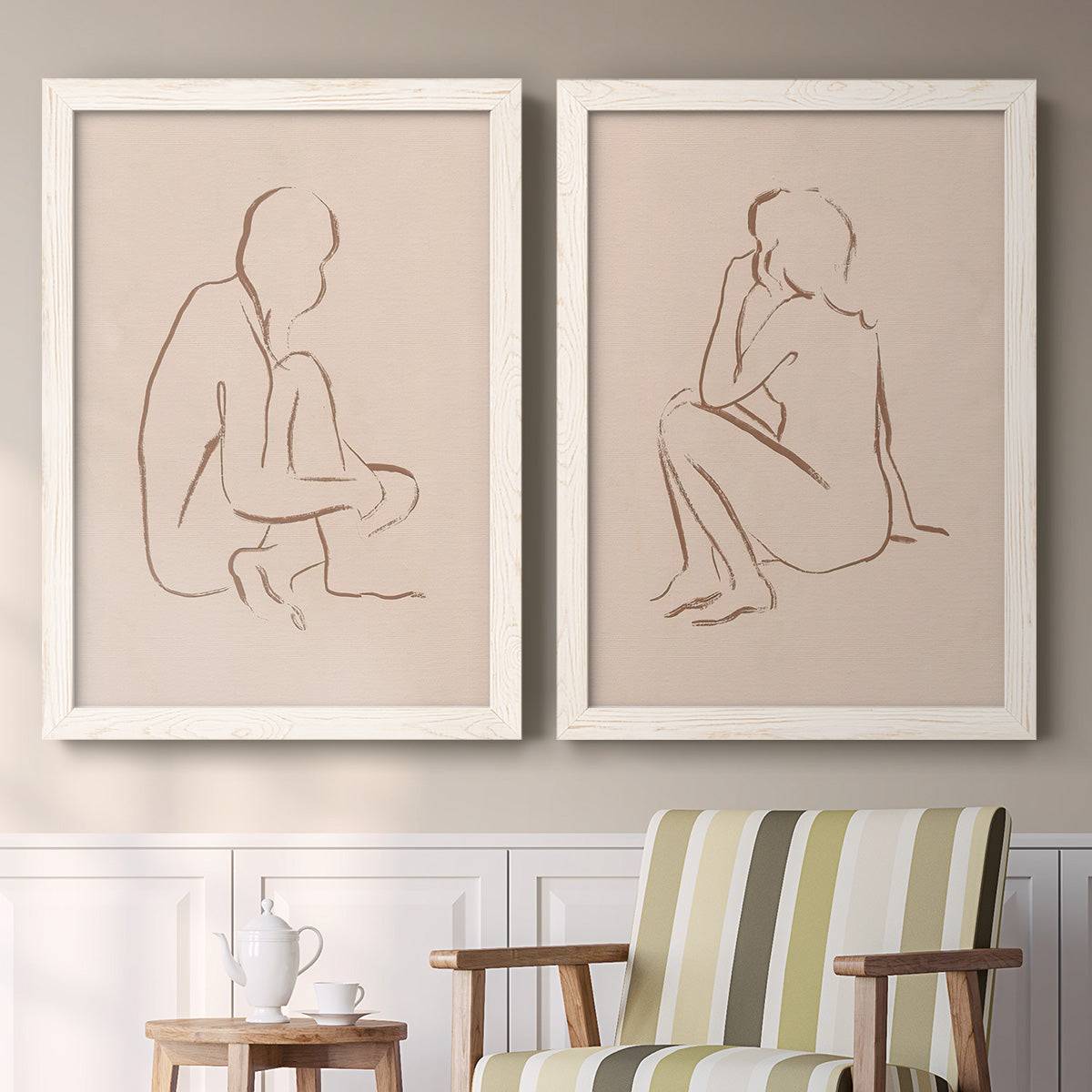 Set of two white barnwood framed canvas prints depicting two minimalist figurative sketches featuring seated female figures drawn with single flowing lines above a sideboard in a cozy sitting room.