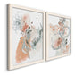 Angled view of a set of two white barnwood framed canvas prints featuring two abstract watercolor botanicals featuring loose blush gray and coral floral gestures.