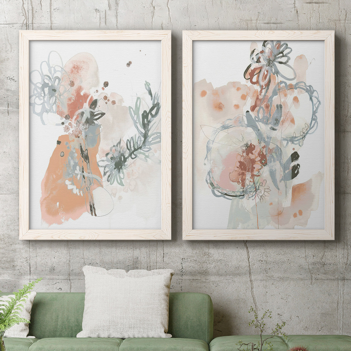 Set of two white barnwood framed canvas prints depicting a coordinated art pair of loose blush gray and coral floral gestures rendered as abstract watercolor botanicals above a sofa in a modern living room.