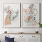 Set of two white barnwood framed canvas prints depicting a coordinated art pair of loose blush gray and coral floral gestures rendered as abstract watercolor botanicals above a dining room sideboard.