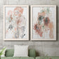 Set of two white barnwood framed canvas prints depicting a coordinated art pair of loose blush gray and coral floral gestures rendered as abstract watercolor botanicals above a sofa in a modern living room.