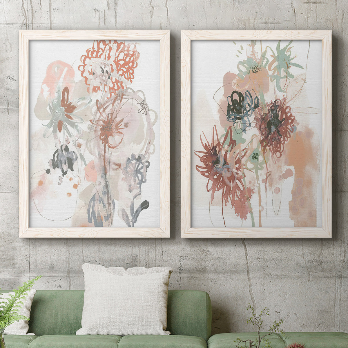 Set of two white barnwood framed canvas prints depicting a coordinated art pair of loose blush gray and coral floral gestures rendered as abstract watercolor botanicals above a sofa in a modern living room.
