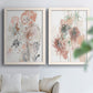 Set of two white barnwood framed canvas prints depicting scribbled petals, translucent washes, and drifting stems arranged across two complementary compositions above a sofa in a bright living space.