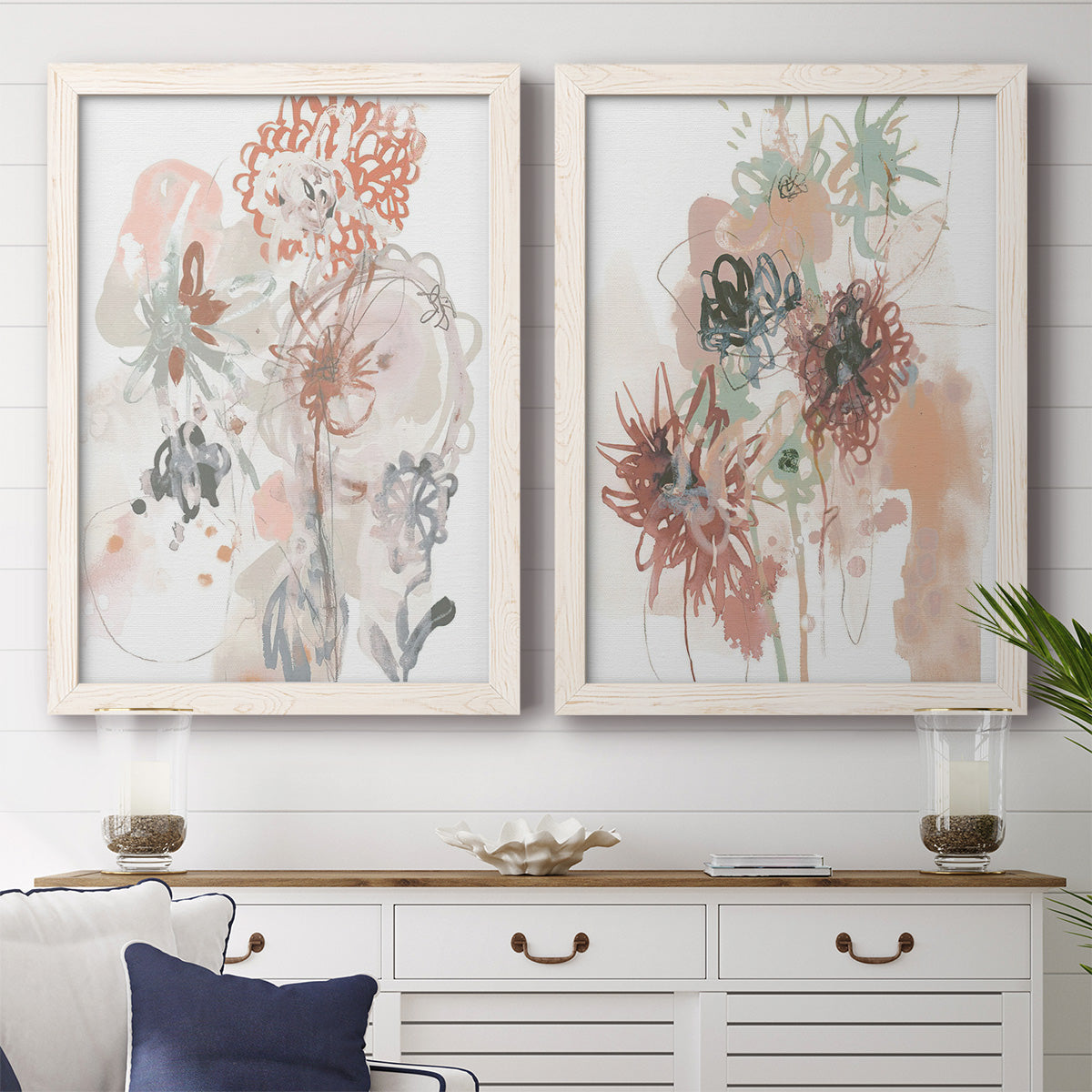 Set of two white barnwood framed canvas prints depicting a coordinated art pair of loose blush gray and coral floral gestures rendered as abstract watercolor botanicals above a dining room sideboard.