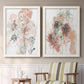 Set of two white barnwood framed canvas prints depicting two abstract watercolor botanicals featuring loose blush gray and coral floral gestures above a sideboard in a cozy sitting room.