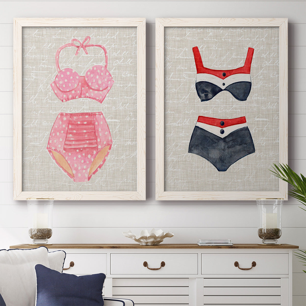 Set of two white barnwood framed canvas prints depicting a coordinated art pair of retro two-piece swimsuits displayed on textured linen grounds rendered as vintage fashion illustrations above a dining room sideboard.