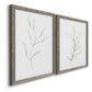 Angled view of a set of two gray barnwood framed canvas prints featuring two minimalist botanical line drawings featuring single continuous-line leafy branches.