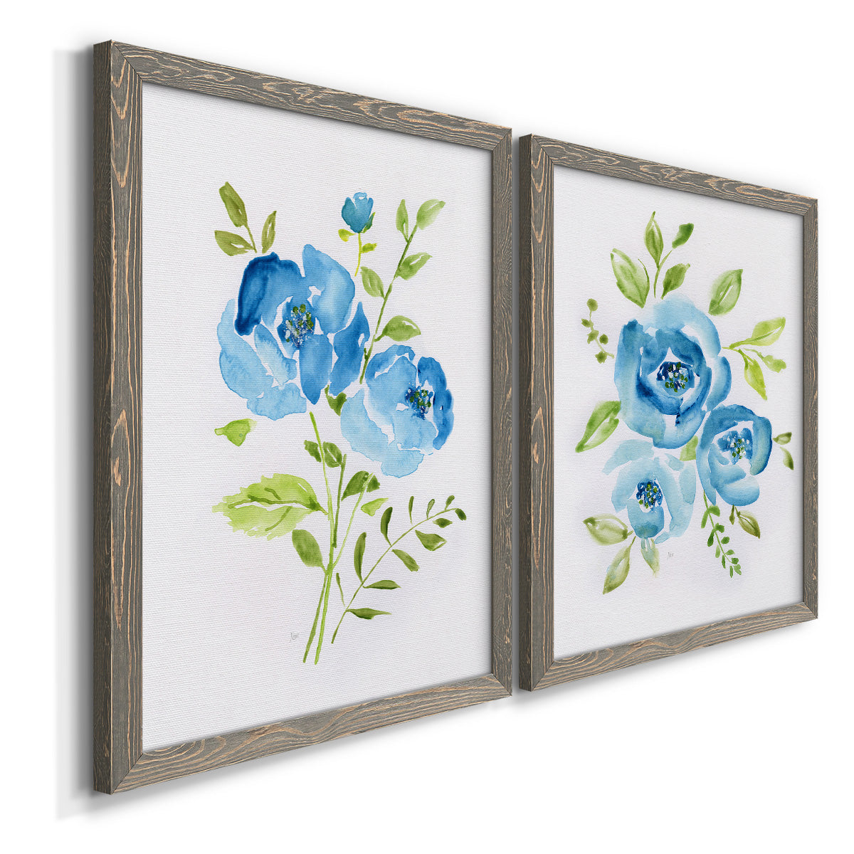 Angled view of a set of two gray barnwood framed canvas prints featuring two contemporary botanical paintings featuring blue watercolor flowers with fresh green leaves.