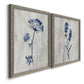 Angled view of a set of two gray barnwood framed canvas prints featuring two rustic monochrome botanical paintings featuring blue wildflower stems on weathered neutral paper.