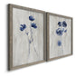 Angled view of a set of two gray barnwood framed canvas prints featuring two rustic monochrome botanical paintings featuring blue wildflower stems on weathered neutral paper.