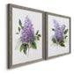 Angled view of a set of two gray barnwood framed canvas prints featuring two romantic traditional floral paintings featuring full purple lilac clusters with green leaves.