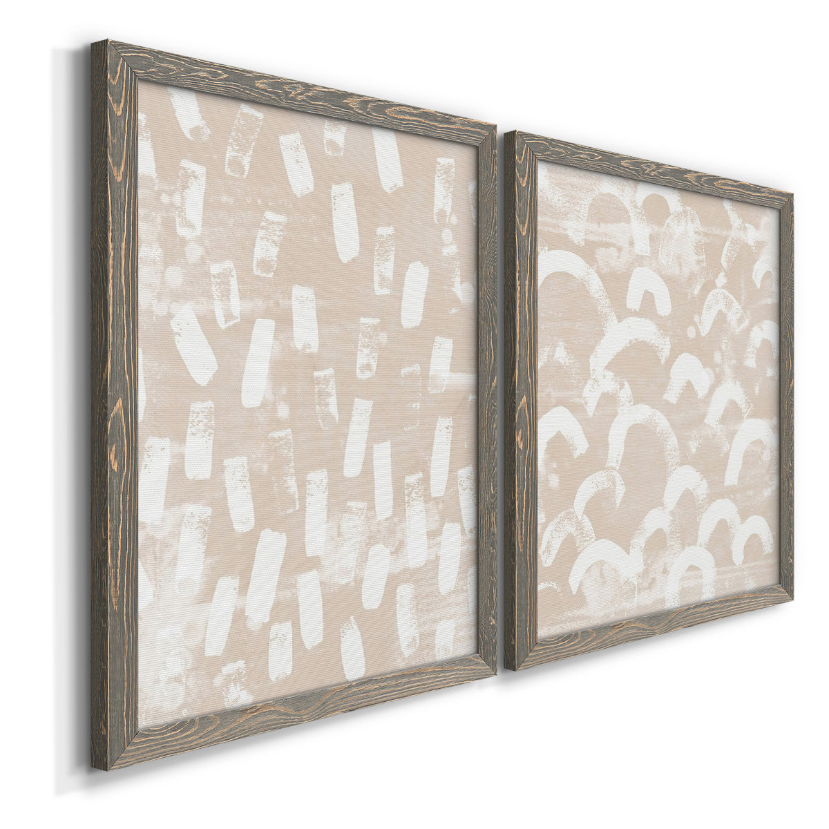 Angled view of a set of two gray barnwood framed canvas prints featuring two tribal-inspired pattern abstracts featuring white hand-painted dashes arcs and chevrons.