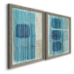 Angled view of a set of two gray barnwood framed canvas prints featuring two graphic geometric abstracts featuring stacked blue ovals behind fine vertical stripes.