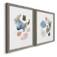 Angled view of a set of two gray barnwood framed canvas prints featuring two airy minimalist abstracts featuring scattered translucent watercolor shapes.