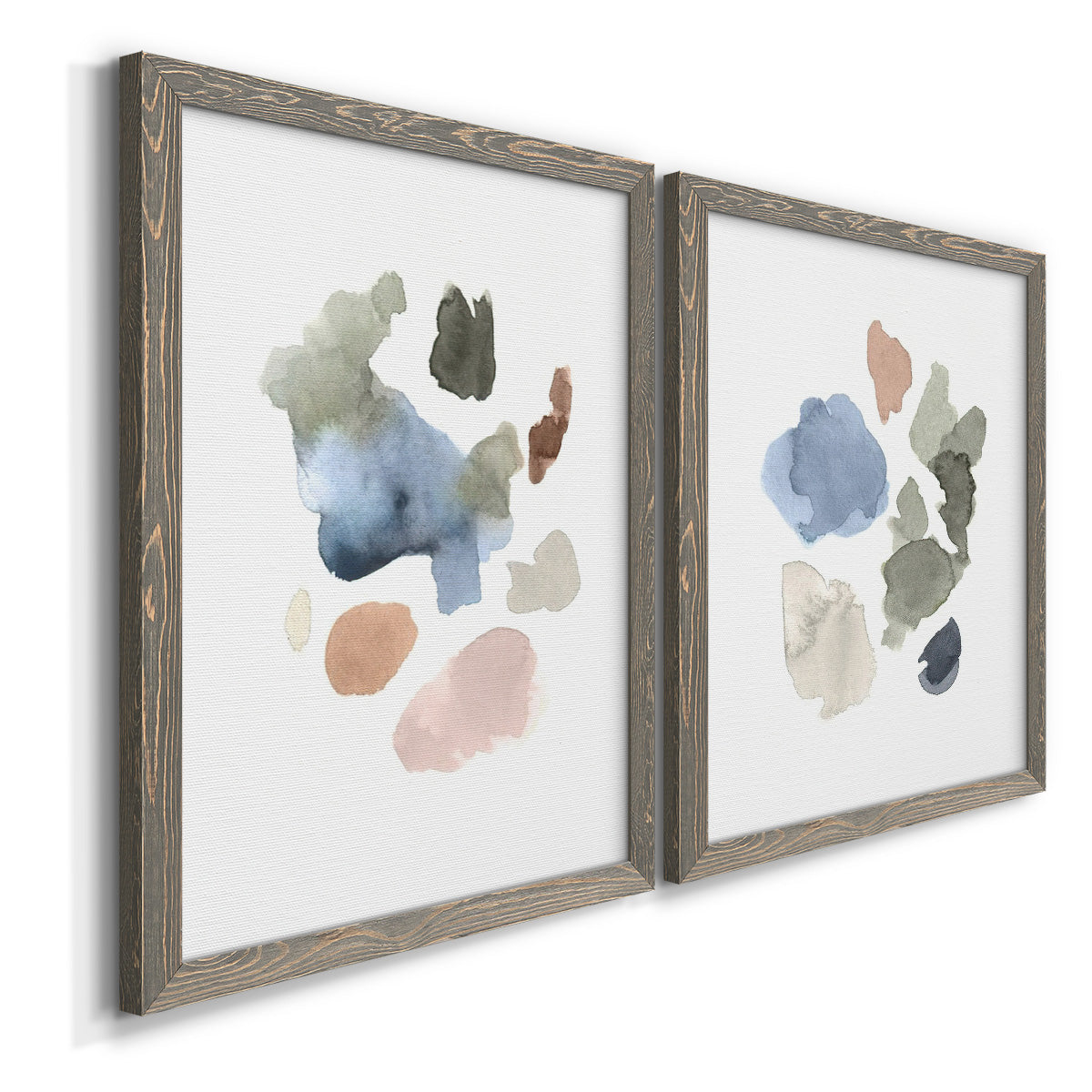 Angled view of a set of two gray barnwood framed canvas prints featuring two airy minimalist abstracts featuring scattered translucent watercolor shapes.