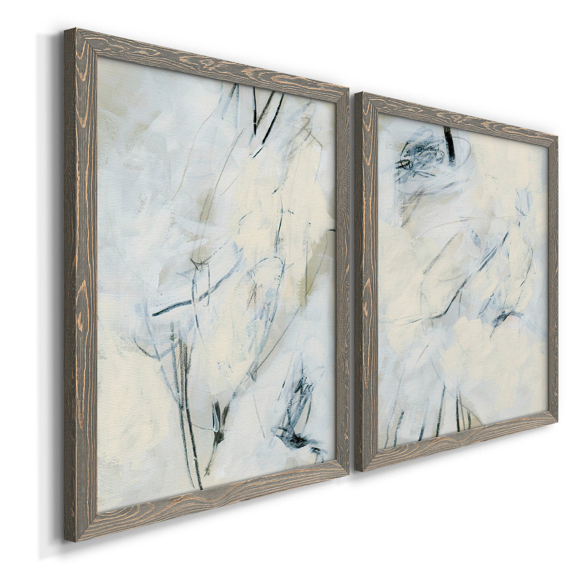 Angled view of a set of two gray barnwood framed canvas prints featuring two airy gestural abstracts featuring pale blue cream and charcoal marks drifting across white.