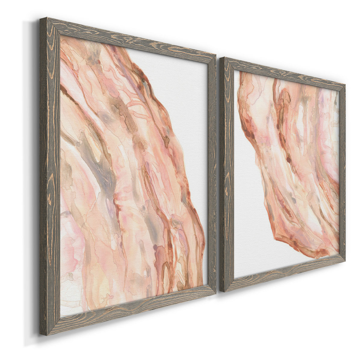 Angled view of a set of two gray barnwood framed canvas prints featuring two soft marble-inspired abstracts featuring flowing blush peach and cream mineral bands.