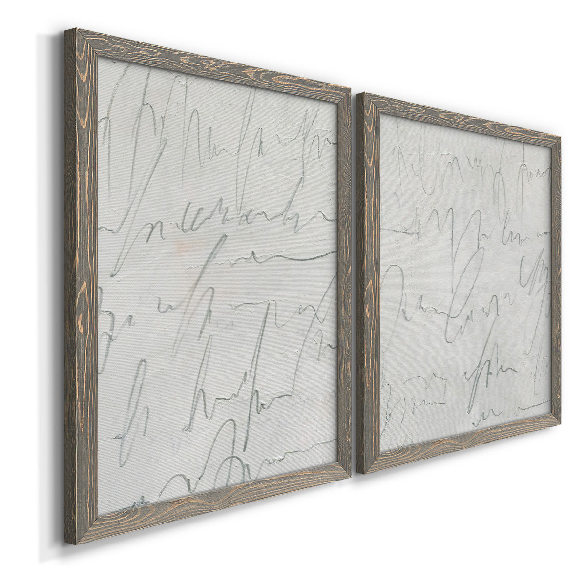 Angled view of a set of two gray barnwood framed canvas prints featuring two minimalist script abstracts featuring faint looping handwriting across pale gray grounds.