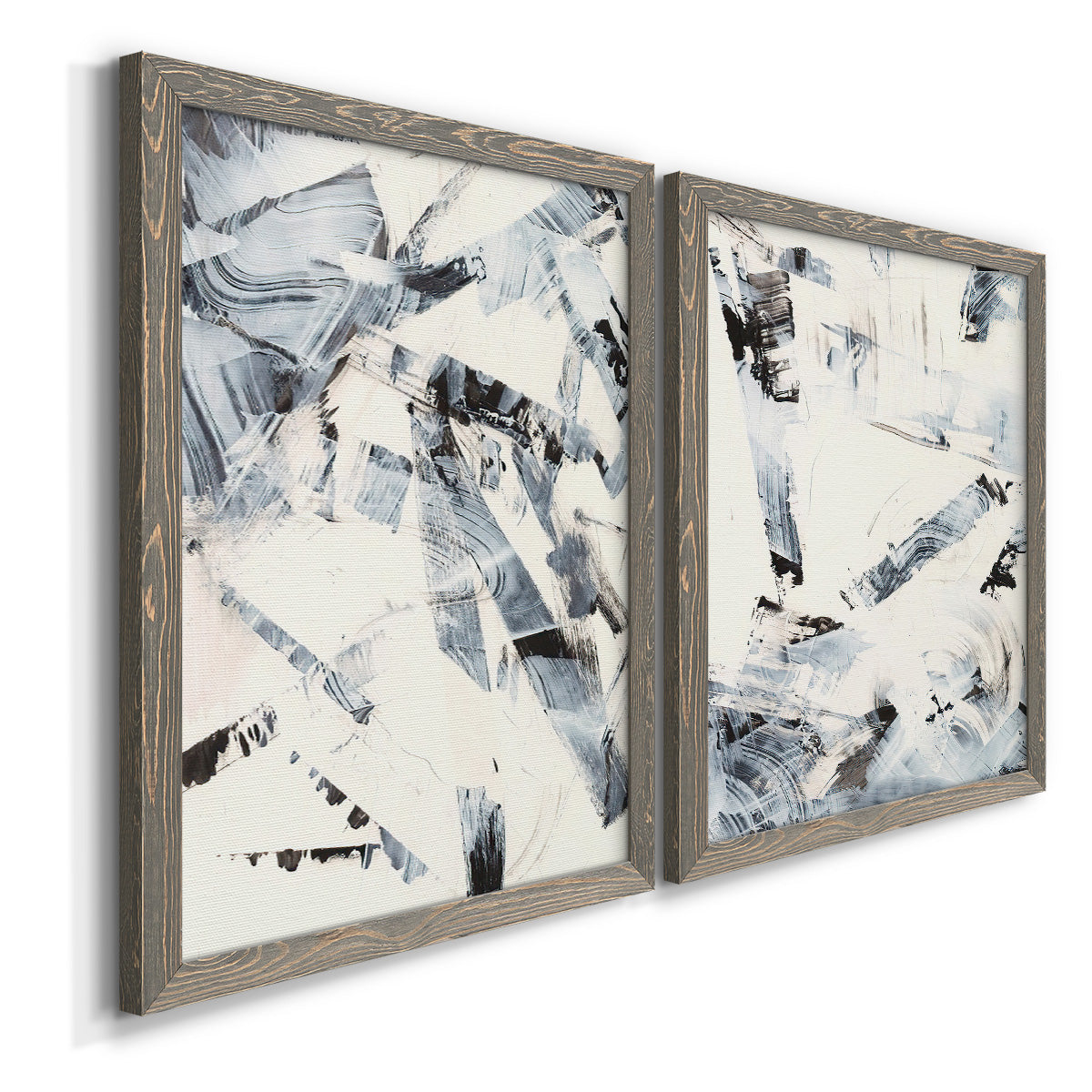 Angled view of a set of two gray barnwood framed canvas prints featuring two high-contrast gestural abstracts featuring angular black and gray brush fragments on white.