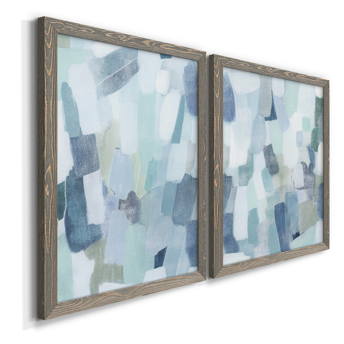 Angled view of a set of two gray barnwood framed canvas prints featuring two cool-toned geometric abstracts featuring fragmented pale blue green gray and white brush blocks.