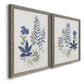 Angled view of a set of two gray barnwood framed canvas prints featuring two rustic botanical illustrations featuring blue fern fronds and small woodland flowers.