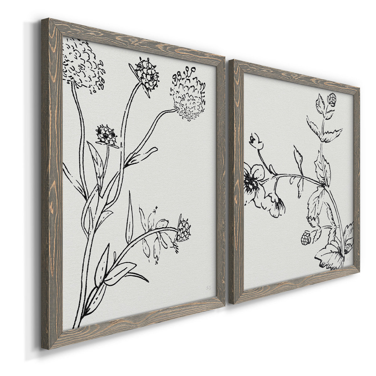 Angled view of a set of two gray barnwood framed canvas prints featuring two minimalist botanical sketches featuring black line drawings of wildflowers and leaves.