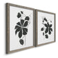 Angled view of a set of two gray barnwood framed canvas prints featuring two minimalist botanical prints featuring black leafy vine silhouettes.