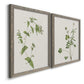 Angled view of a set of two gray barnwood framed canvas prints featuring two rustic minimalist botanical studies featuring delicate wildflower and leafy stems.