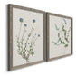 Angled view of a set of two gray barnwood framed canvas prints featuring two rustic minimalist botanical studies featuring delicate wildflower and leafy stems.
