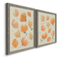 Angled view of a set of two gray barnwood framed canvas prints featuring two airy watercolor floral paintings featuring loose peach-orange tulip-like blossoms.