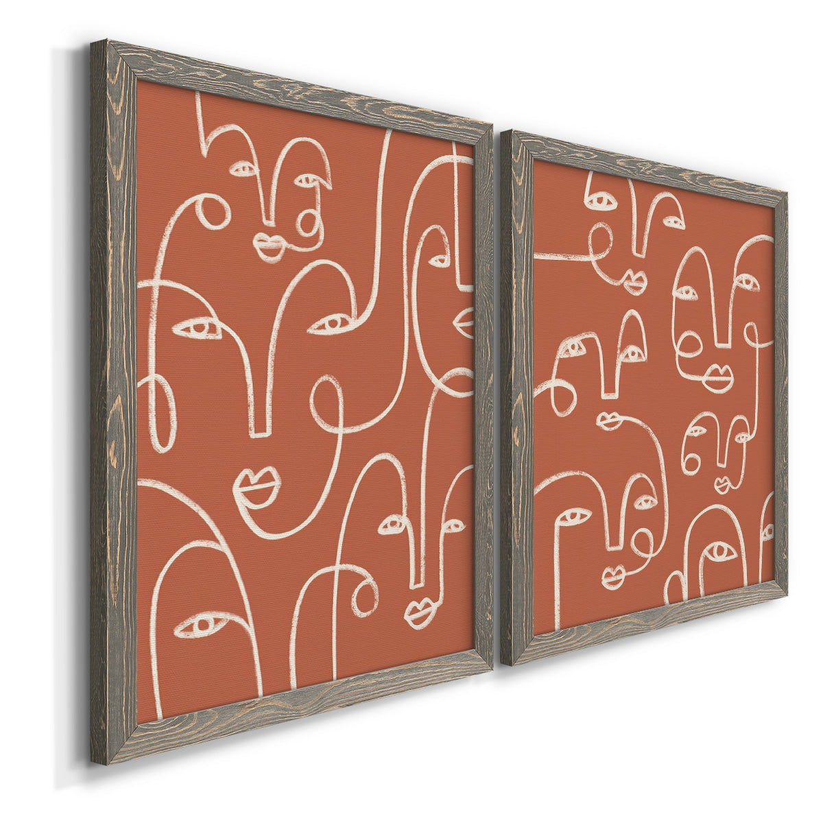 Angled view of a set of two gray barnwood framed canvas prints featuring two graphic portrait patterns featuring many continuous-line faces across terracotta grounds.