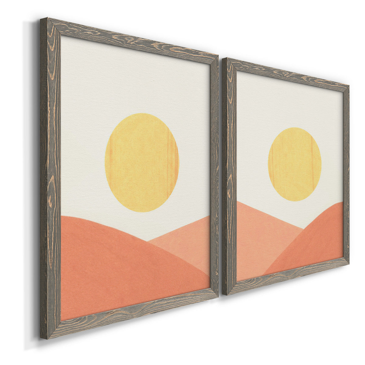 Angled view of a set of two gray barnwood framed canvas prints featuring two minimalist boho landscapes featuring yellow suns rising over terracotta geometric hills.
