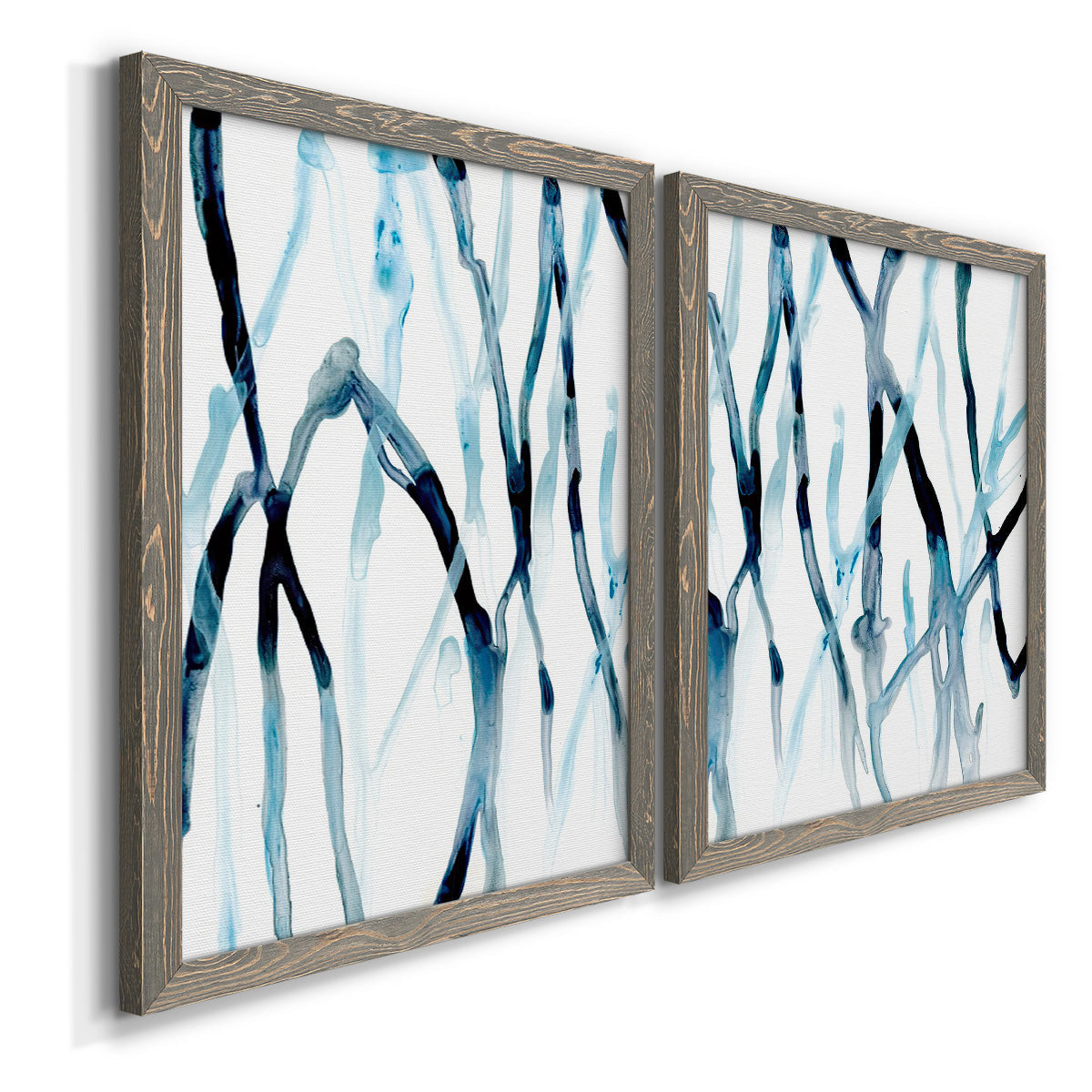 Angled view of a set of two gray barnwood framed canvas prints featuring two fluid organic abstracts featuring branching watercolor lines drifting across white.