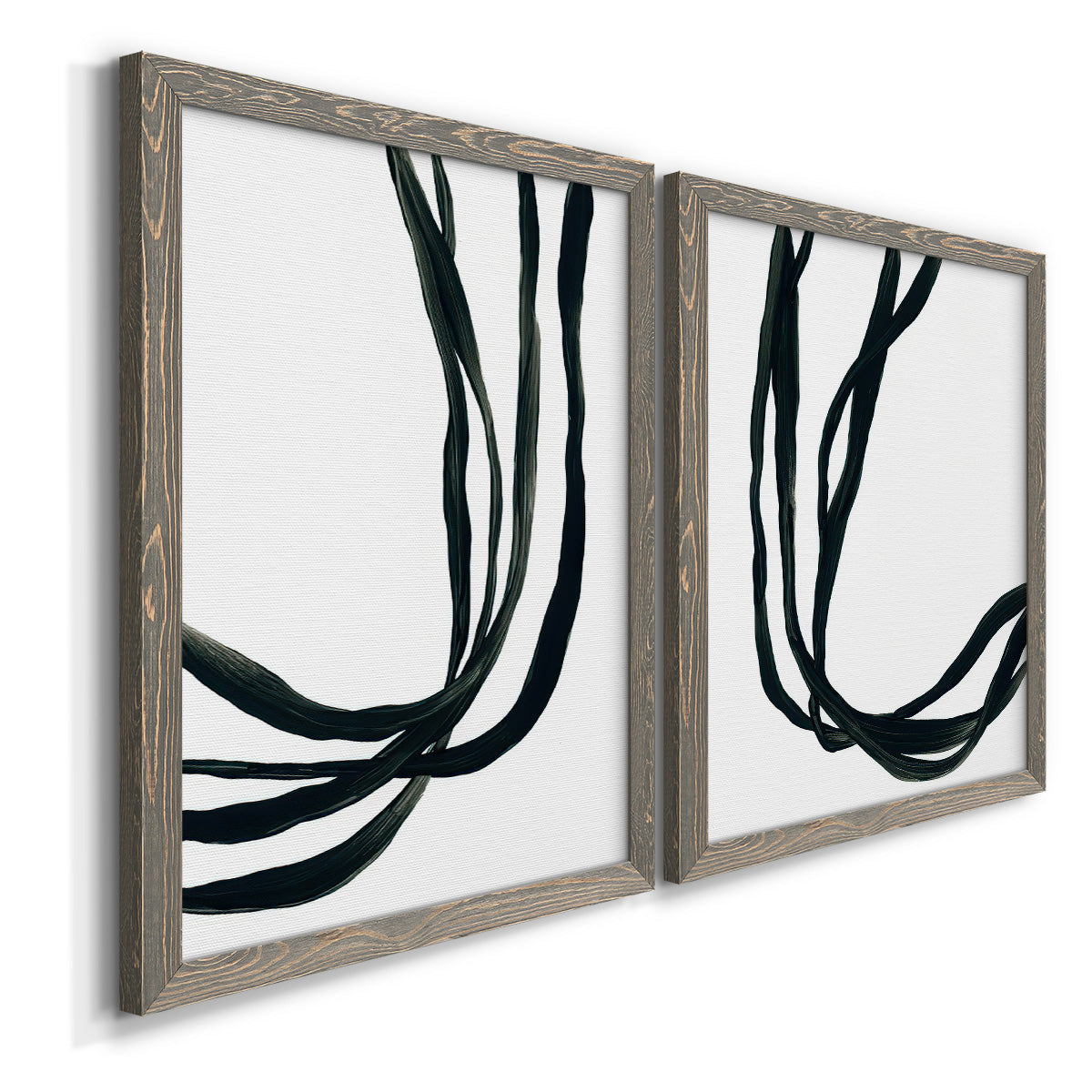 Angled view of a set of two gray barnwood framed canvas prints featuring two minimalist gestural line abstracts featuring flowing black ribbon-like lines.