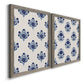 Angled view of a set of two gray barnwood framed canvas prints featuring two repeating blue floral patterns with stylized bouquets arranged across warm white backgrounds.