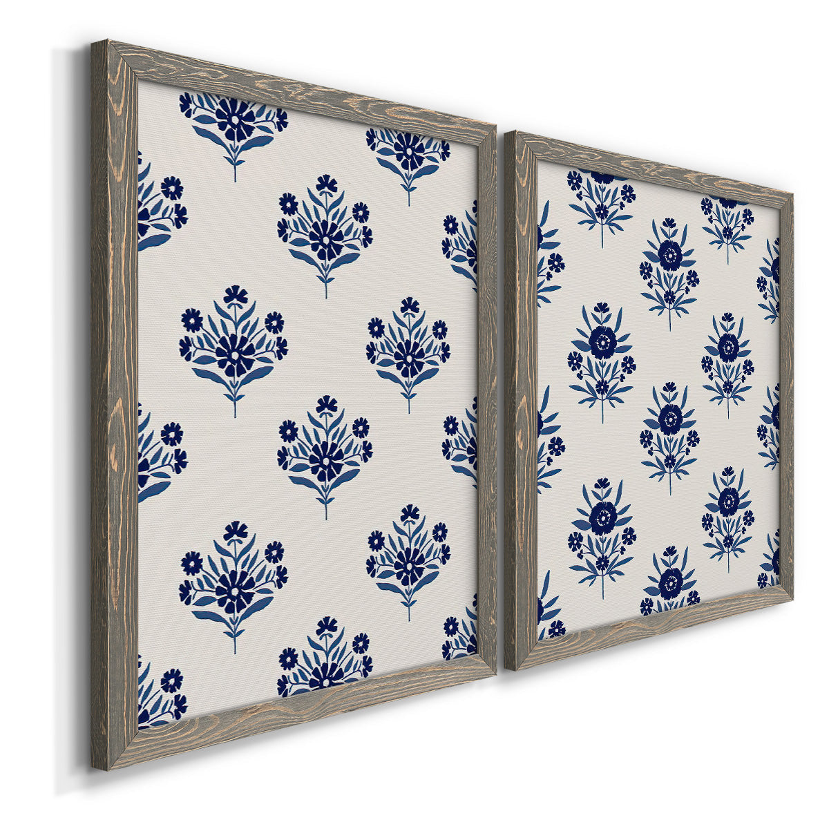 Angled view of a set of two gray barnwood framed canvas prints featuring two repeating blue floral patterns with stylized bouquets arranged across warm white backgrounds.