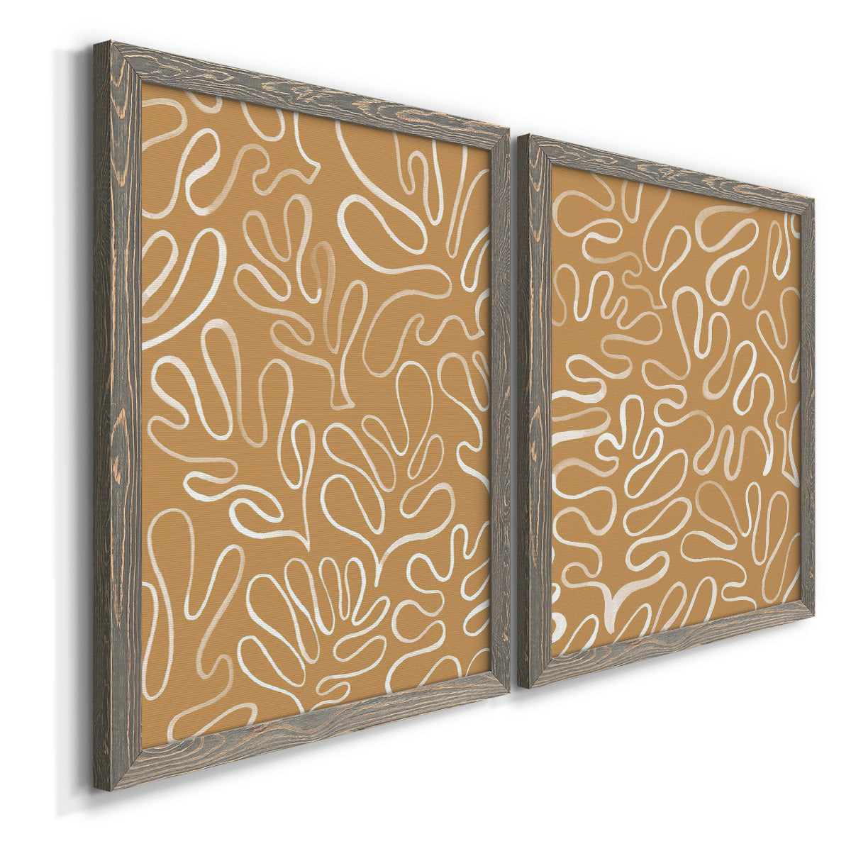 Angled view of a set of two gray barnwood framed canvas prints featuring two graphic botanical pattern abstracts featuring continuous white organic lines over solid ochre and blush fields.