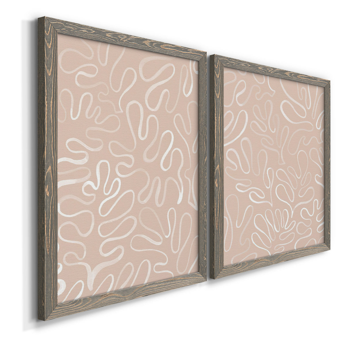 Angled view of a set of two gray barnwood framed canvas prints featuring two graphic botanical pattern abstracts featuring continuous white organic lines over solid ochre and blush fields.
