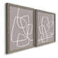 Angled view of a set of two gray barnwood framed canvas prints featuring two minimalist geometric line art featuring overlapping white continuous-line loops on taupe.