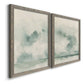 Angled view of a set of two gray barnwood framed canvas prints featuring two minimalist watercolor seascapes with misty green clouds calm horizons and pale reflective water.