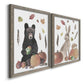 Angled view of a set of two gray barnwood framed canvas prints featuring a watercolor woodland animal pair with a bear rabbit hedgehog pumpkins fruit acorns and falling leaves.