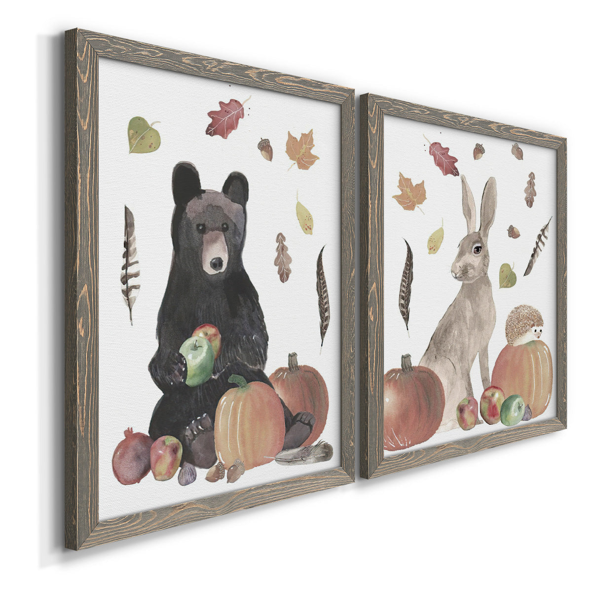 Angled view of a set of two gray barnwood framed canvas prints featuring a watercolor woodland animal pair with a bear rabbit hedgehog pumpkins fruit acorns and falling leaves.